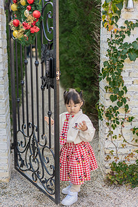 儿童米米摄影照片_米奇格子裙下午儿童花园站着推门摄影图配图