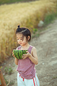 夏日儿童人像白天小男孩麦田吃西瓜摄影图配图