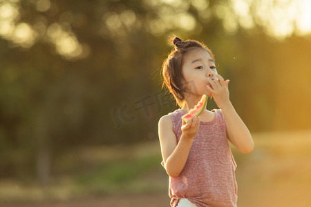 夏日儿童人像夕阳可爱小男生田野里吃西瓜摄影图配图