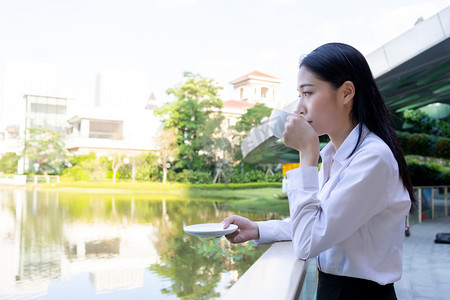 商务下午白领女性湖边喝咖啡摄影图配图