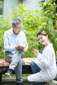 老年健康白天老人和女医生户外记录病情摄影图配图