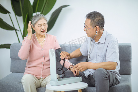 老年人摄影照片_医疗养生白天两位老人家里量血压摄影图配图