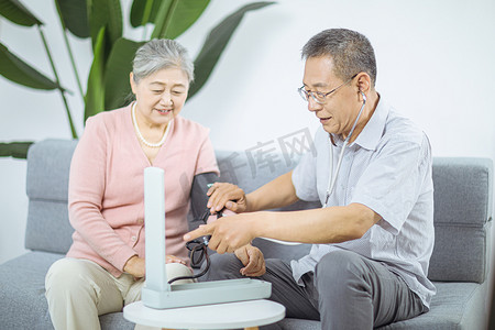 医疗养生白天两位老人室内看血压计摄影图配图