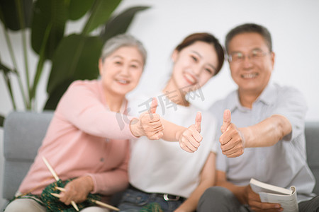 家里郁闷女摄影照片_家庭和谐白天一家三口家里竖大拇指摄影图配图