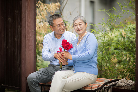 老年爱情白天一对老夫妻户外送玫瑰花摄影图配图
