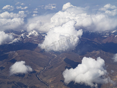 下云朵摄影照片_航拍风光白天白云雪山飞机航拍白云下的雪山摄影图配图