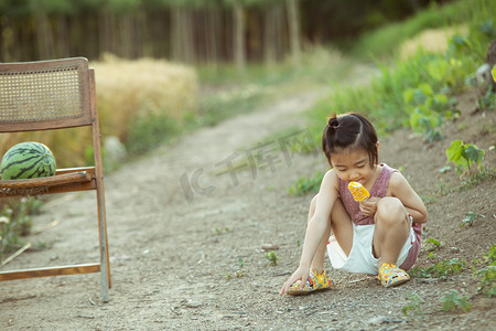 夏日儿童人像白天一个男孩麦田林间小路蹲着吃冰棍摄影图配图