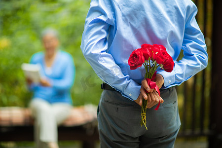 重阳节老人摄影照片_老年生活白天拿着玫瑰花的老人户外送惊喜摄影图配图
