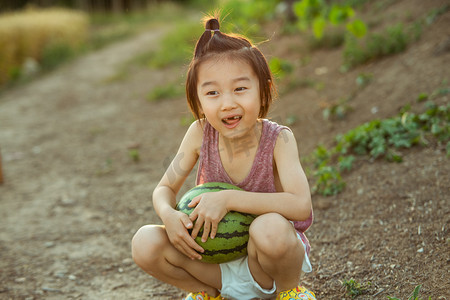 夏日儿童摄景白天长发小男孩林间小路开心的抱着大西瓜摄影图配图