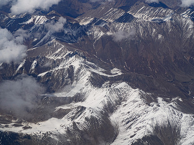 山川俯瞰摄影照片_航拍风光白天白云雪山飞机上俯瞰雪山美景摄影图配图
