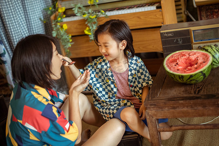 西瓜男孩摄影照片_夏日亲子人像白天母子两人室内一起吃西瓜摄影图配图