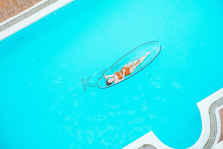 比基尼摄影照片_夏日清凉白天比基尼美女泳池水晶船躺着摄影图配图