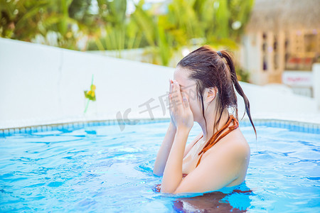 夏日清新白天游泳的美女泳池捂脸摄影图配图