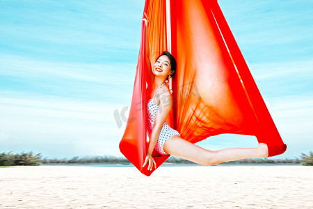 比基尼美女摄影照片_运动健身瑜伽白天比基尼美女户外沙滩空中瑜伽体式摄影图配图