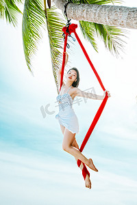 夏日沙滩美女摄影照片_运动瑜伽白天比基尼美女户外沙滩空中瑜伽体式摄影图配图