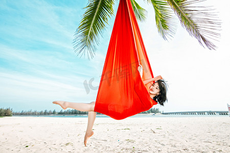 运动健身白天练习空中瑜伽的美女户外沙滩抓拍摄影图配图