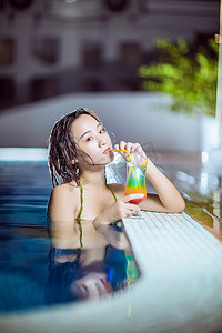 杂志写真摄影照片_泳池写真夜晚比基尼美女户外泳池喝鸡尾酒摄影图配图