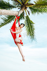 空中瑜伽白天比基尼美女椰子树下空中瑜伽体式摄影图配图