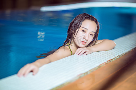 夏天美女泳池晚上比基尼美女户外泳池趴在泳池边摄影图配图