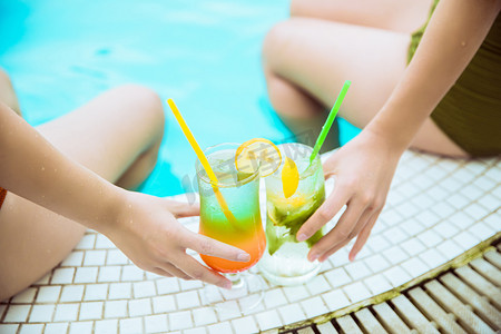 夏日清凉白天两杯鸡尾酒泳池边端着鸡尾酒摄影图配图