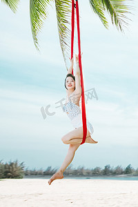 运动瑜伽白天穿着比基尼的美女户外沙滩空中瑜伽体式摄影图配图