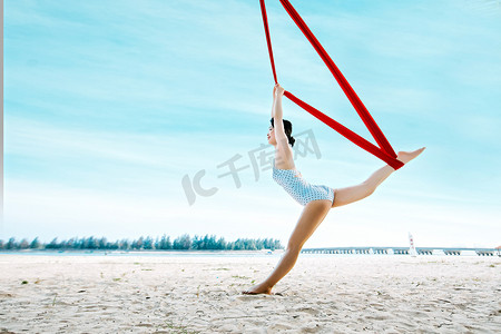 空中瑜伽白天联系空中瑜伽的美女户外沙滩空中瑜伽体式摄影图配图