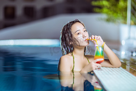 比基尼美女写真摄影照片_夏天美女夜晚比基尼美女泳池边喝鸡尾酒摄影图配图