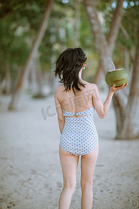 泳衣美女摄影照片_背影夏天美女沙滩手举椰子摄影图配图