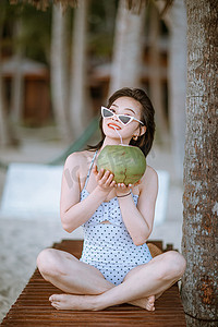 海南旅行摄影照片_人物形象白天美女户外手举椰子摄影图配图