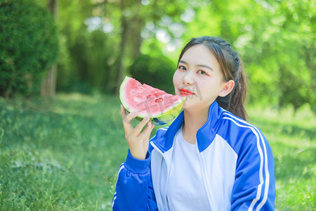 夏日白天少女草坪吃西瓜摄影图配图