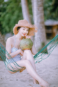 海南旅行摄影照片_人物夏天美女海边喝椰汁摄影图配图