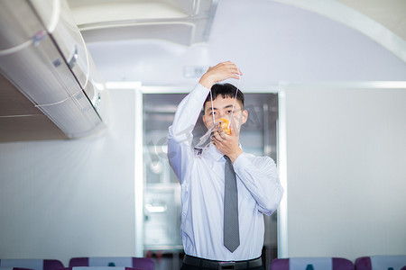 空乘白天男乘务员客舱内戴上氧气面罩摄影图配图