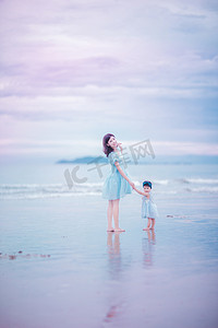 亲子旅行摄影照片_亲子时光傍晚年轻妈妈和女儿沙滩手拉手摄影图配图