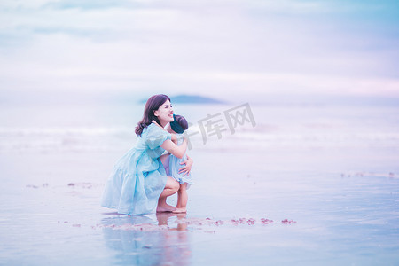 母亲节旅游摄影照片_亲子关系傍晚母女俩沙滩拥抱摄影图配图