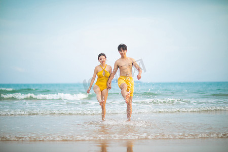情侣沙滩摄影照片_亲密关系白天一对情侣沙滩手拉手奔跑摄影图配图