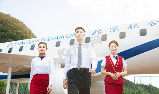 空乘人员白天两位女乘务员和一位男乘务员机舱外站立摄影图配图