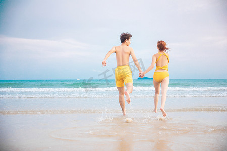情人节白天一对情侣沙滩手拉手奔跑摄影图配图