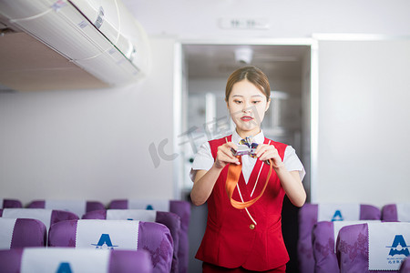 安全须知摄影照片_安全飞行须知白天空姐客舱内展示氧气面罩摄影图配图