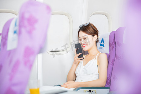 出行白天飞机上的女乘客飞机客舱内语音聊天摄影图配图