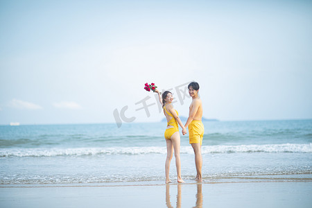爱情白天一对情侣沙滩拿着玫瑰花回头望摄影图配图