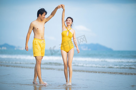 情侣沙滩摄影照片_爱情白天一堆年轻的情侣沙滩手拉手摄影图配图