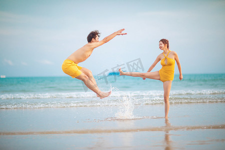 搞笑情侣图摄影照片_情人节白天搞笑情侣沙滩踢人摄影图配图