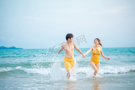 情侣沙滩摄影照片_爱情白天一对情侣沙滩手拉手情侣摄影图配图