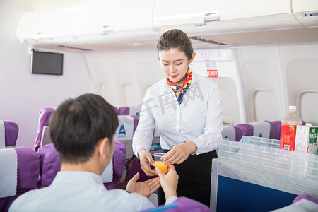 客舱服务白天空姐和男乘客客舱内部递饮料摄影图配图