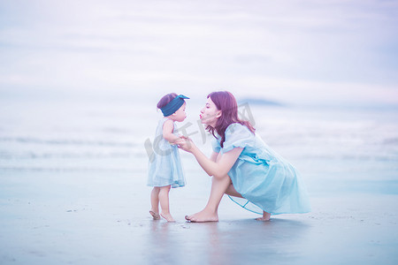 旅行粉色摄影照片_亲子时光白天母女俩沙滩亲吻摄影图配图