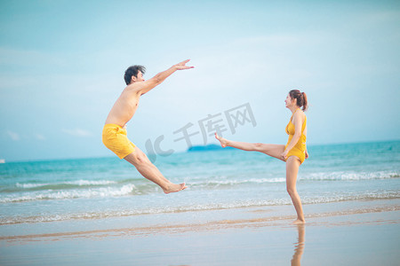 海边情侣摄影照片_爱情情人节白天一对搞笑情侣沙滩踢人摄影图配图