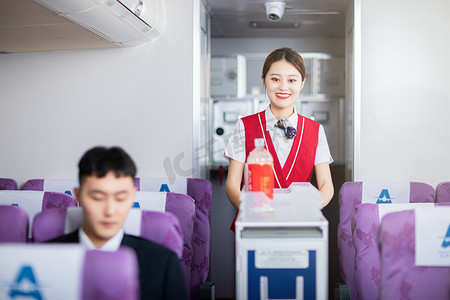 乘客摄影照片_客舱服务白天空姐和男乘客飞机客舱内推饮料车摄影图配图