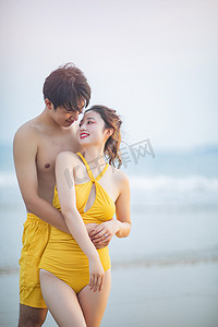 海边情侣摄影照片_爱情情人节白天一对情侣户外沙滩拥抱对视摄影图配图