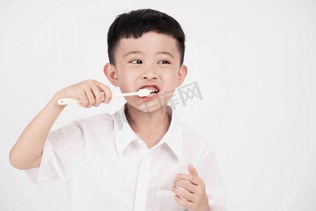 小朋友念儿歌摄影照片_刷牙白天男孩室内牙刷牙缸摄影图配图