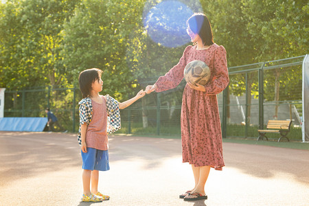 孩子加油摄影照片_亲子夏日人像白天母子二人操场拉手加油摄影图配图